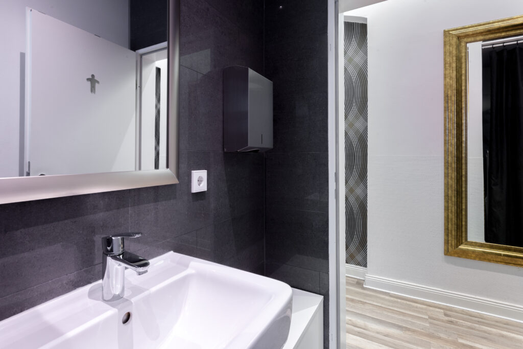 Detailansicht des weißen Waschbeckens mit Armatur und Wandregalen