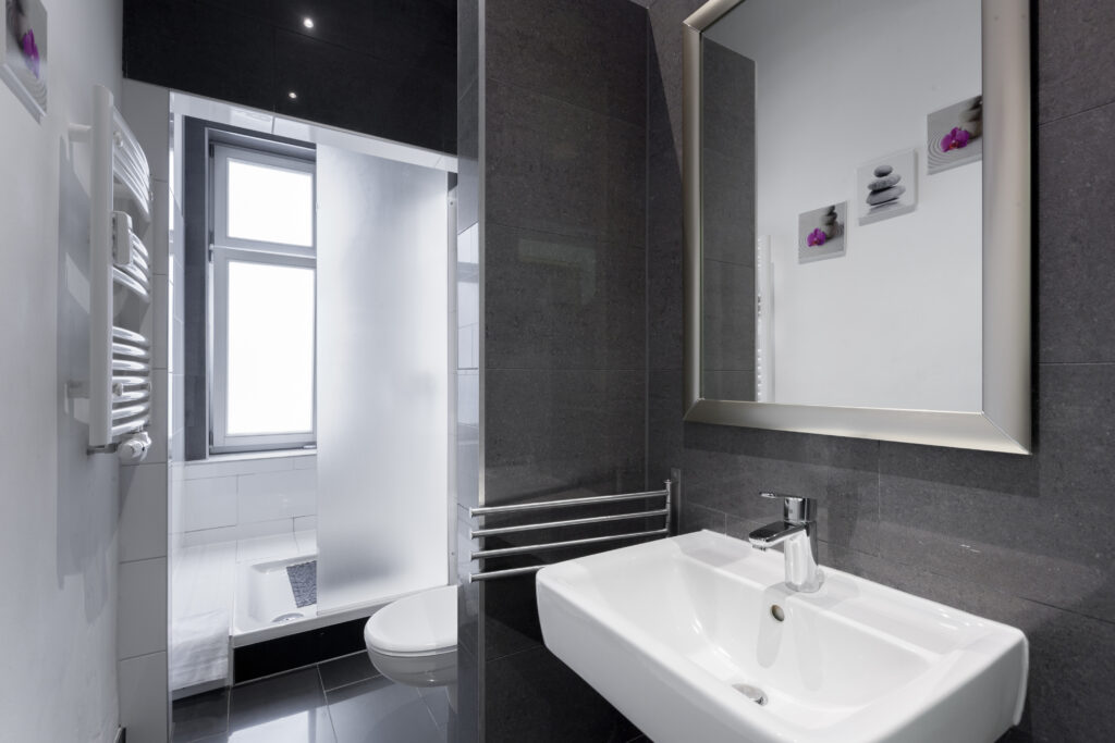 Modernes Badezimmer mit dunklen Fliesen, Waschtisch und Spiegelschränken